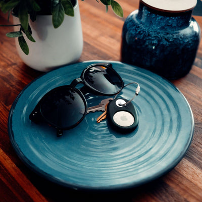 SiliRing with keys attached sitting on a dish next to sunglasses