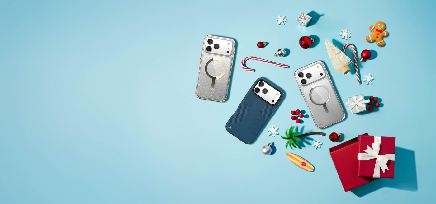 Three iPhones in Speck cases lie flat down on a light blue surface with various Christmas items like candy canes, snowflakes, and ornaments surrounding them