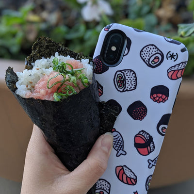 Hand holding a sushi roll and an iPhone with the Presidio Inked:Sushi Collection case