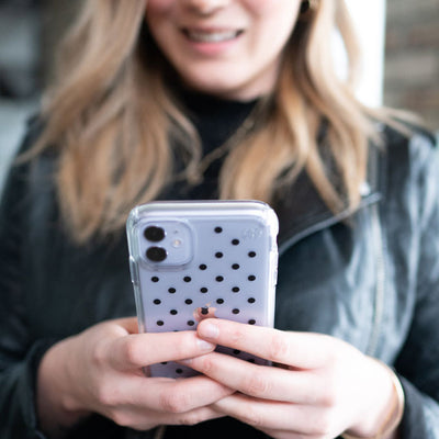 Woman holding an iPhone wrapped in a Presidio Clear + Print: Stripes and Spots Collection case