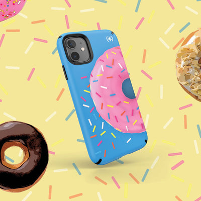 Graphic of donuts and sprinkles on a yellow background with Speck's Presidio Edition: Sprinkled Donut Collection case on an iPhone in the center