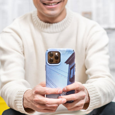 A man in a sweater holding with both hands an iPhone with the Presidio Edition: Read Between The Lines Collection case on it