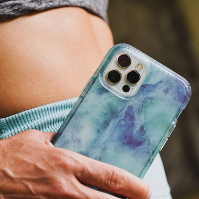 Close-up of the waist of a woman in workout gear with her hand holding an iPhone with the Presidio Edition: Crystal Clouds Collection case on it