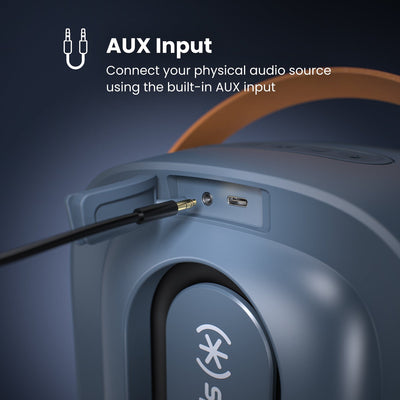 Close-up of the connection ports panel on the back of the speaker with a cable going into the auxiliary jack. AUX input - connect your physical audio source using the built-in AUX input#color_dark-grey-chrome-tan